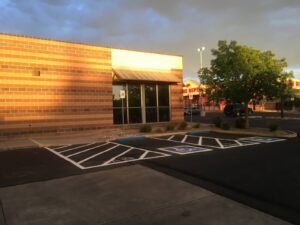 Freshly paved commercial parking lot with marked accessible spaces and storefront building, highlighting spring asphalt inspection and maintenance conditions.