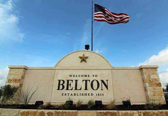 Welcome sign for Belton, Texas (established 1850) with a stone monument, star emblem, and American flag flying above.