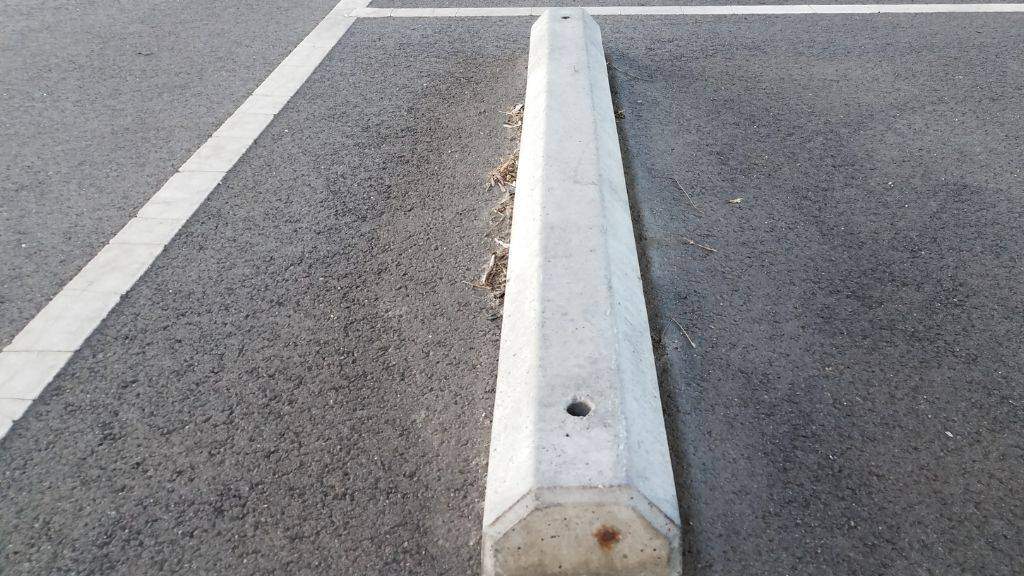 Concrete wheel stop precast bumper installed in a commercial parking space for ADA compliance and vehicle control 
